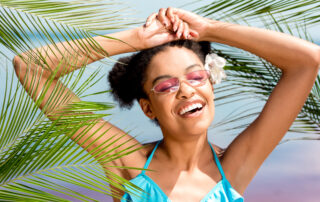 Smiling person outdoors in Trinidad sun wearing glasses, vibrant and relaxed